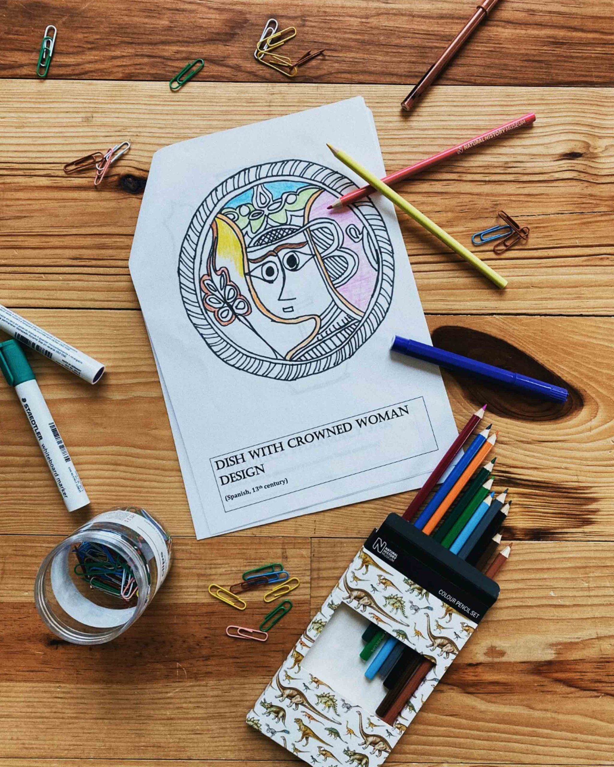 Image of colouring book page partly coloured in, with colouring pencils scattered around it