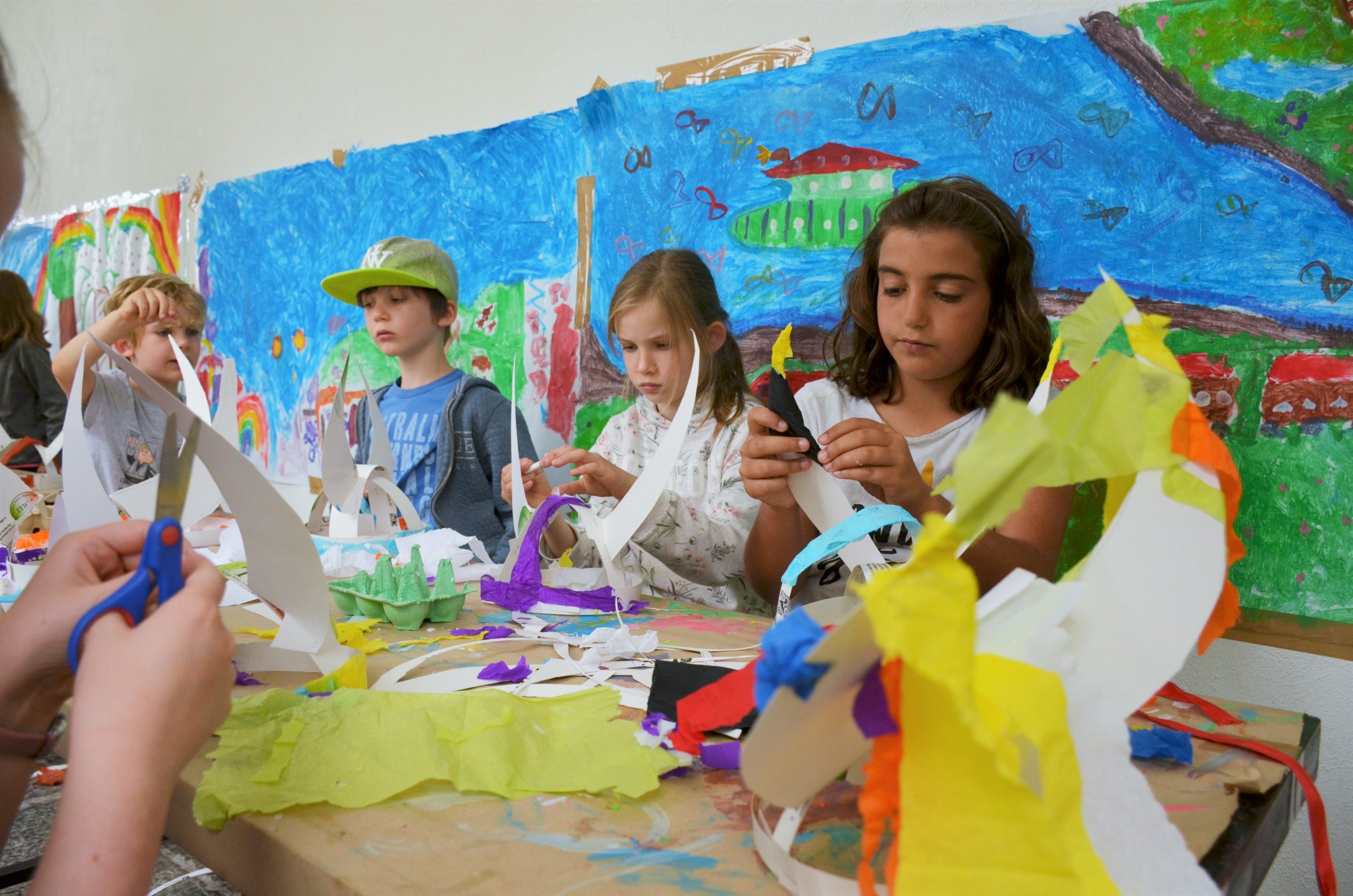 A group of 5 children using card and coloured paper to make a helmet.