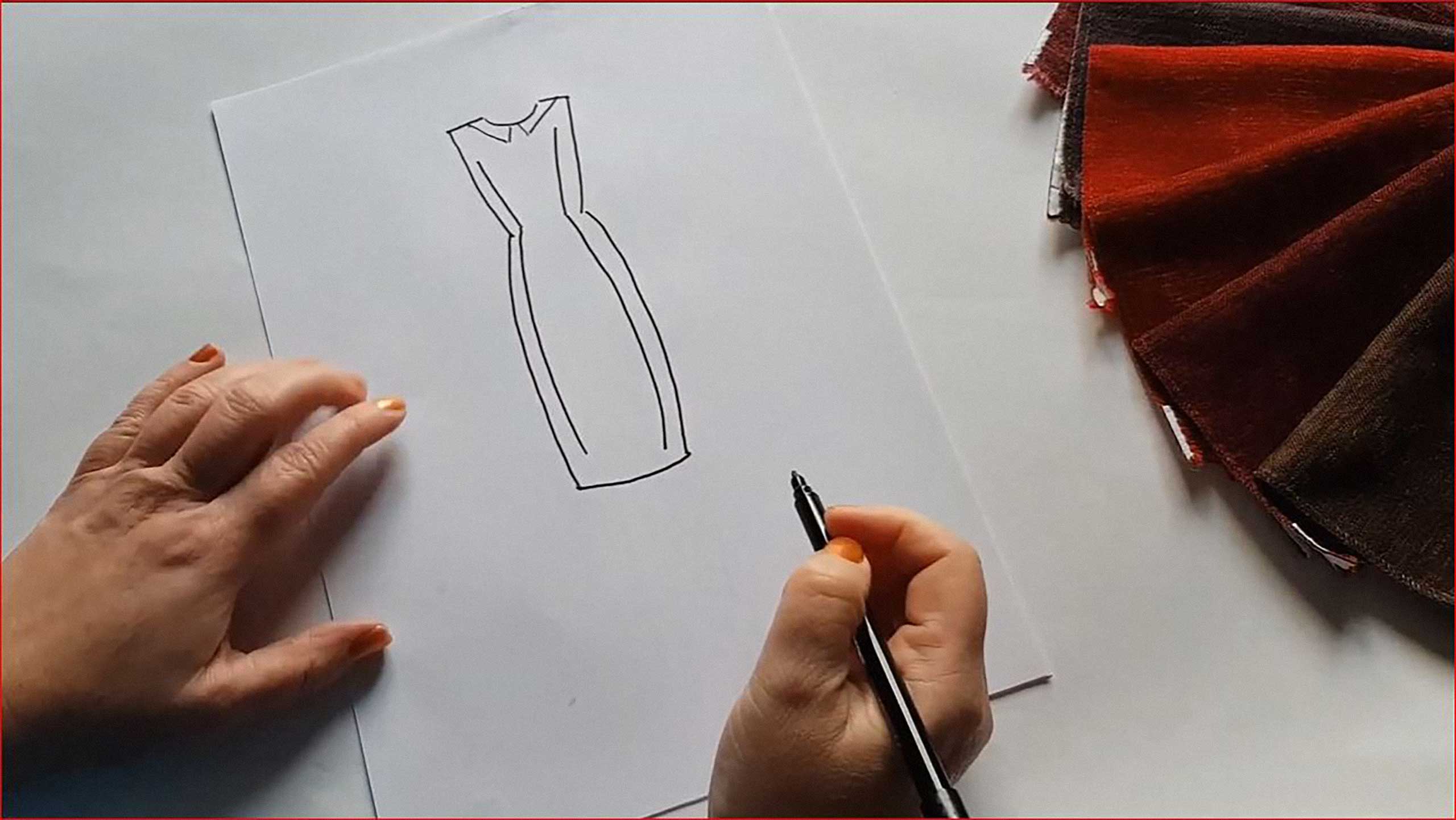Design an Outfit .Two hands hold a pen above a drawing of a sleeveless collared dress. Next to them are an array of red fabrics