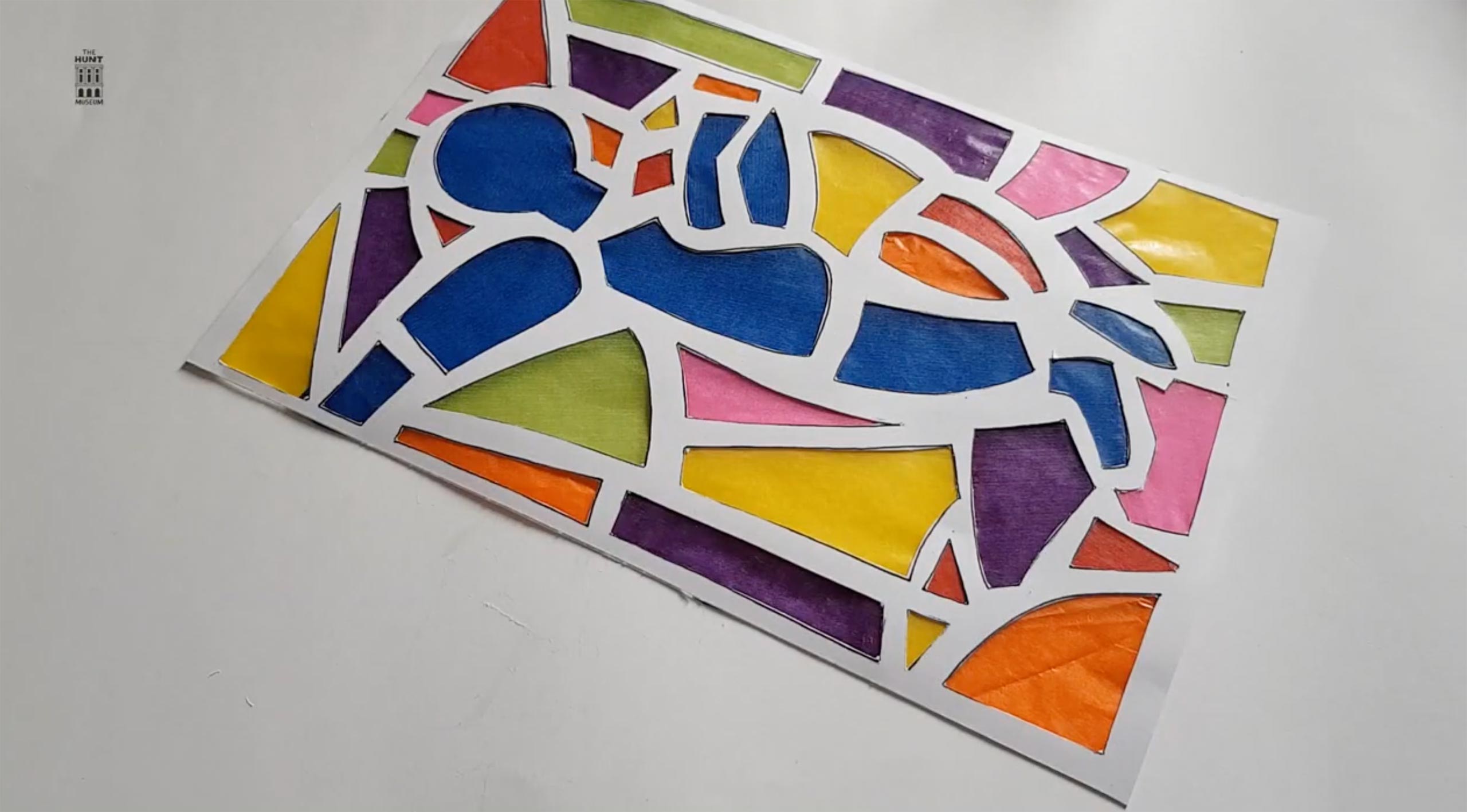 A DIY stained glass window, using paper with shapes cut out, and coloured tissue paper as the coloured glass.