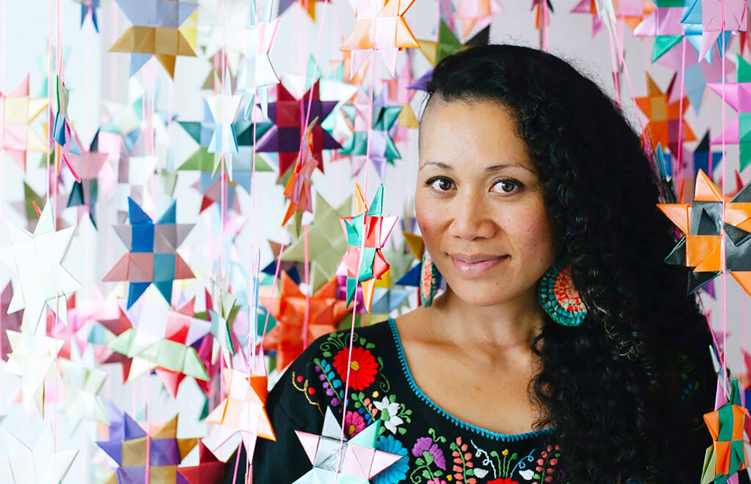 A woman standing amongst origami stars hanging from strings