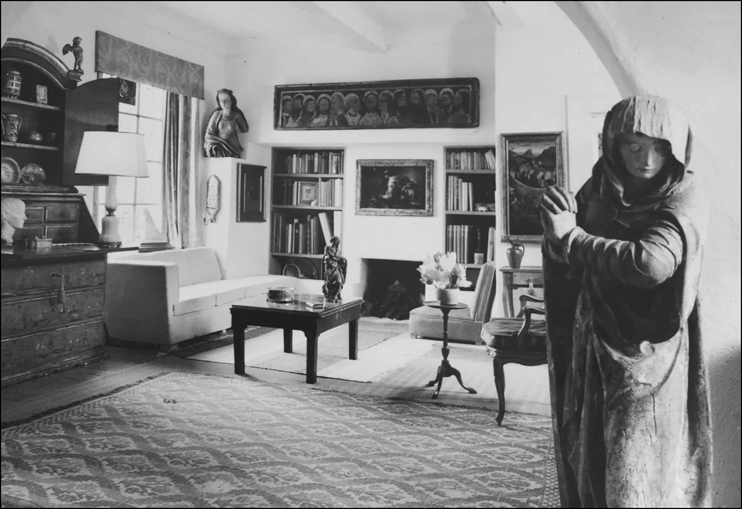 Hunt Collection. A room with couches, coffee table, cabinet, and shelves with books. There are two statues on either side of the room, and a small statuette on the coffee table.
